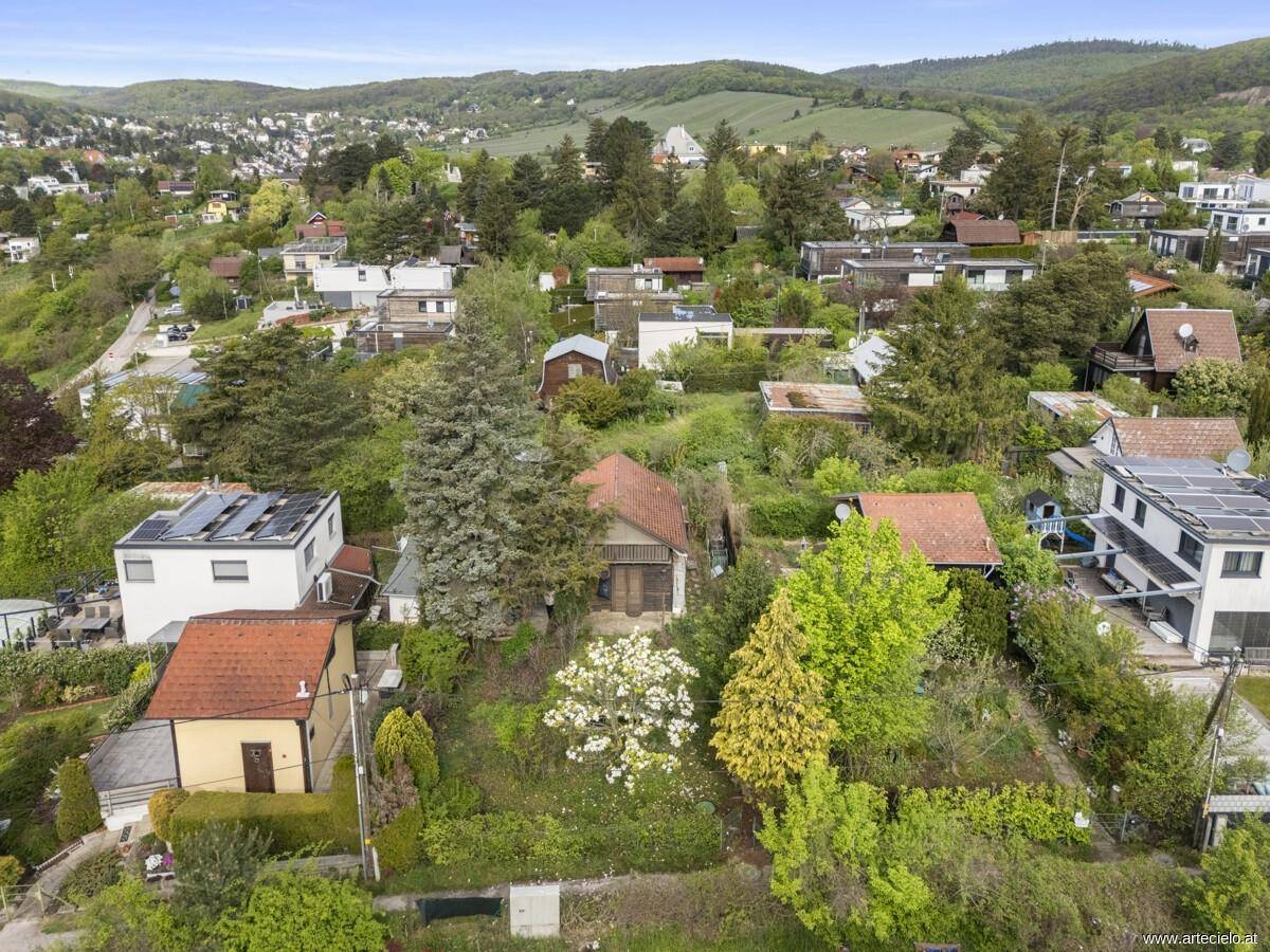 Weitläufige Luftaufnahme der Liegenschaft in einer grünen Hügellandschaft mit Fernblick.