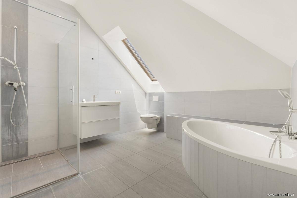 Modernes Badezimmer mit Badewanne, begehbarer Dusche, Dachfenster und grauen Fliesen.