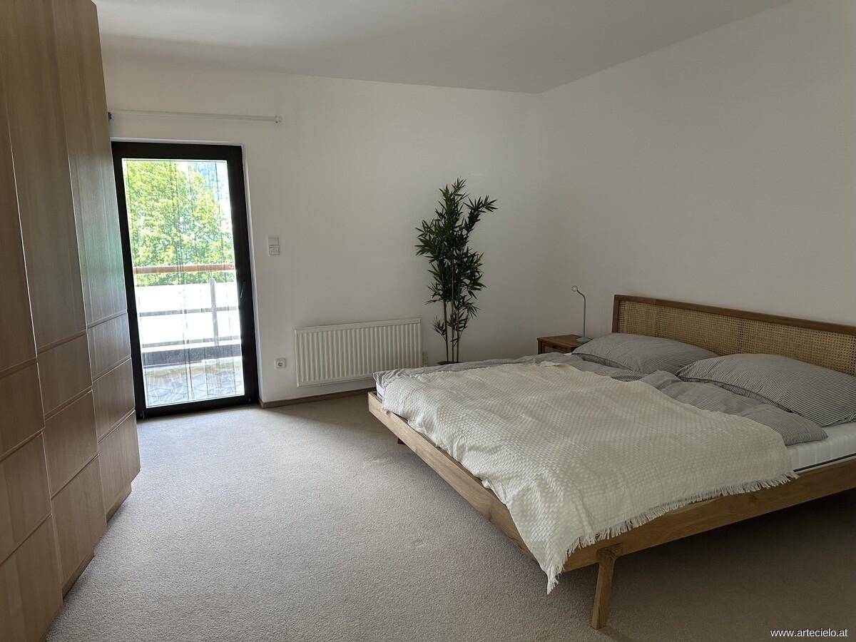 Helles Schlafzimmer mit Doppelbett, Teppichboden und direktem Zugang zum Balkon.