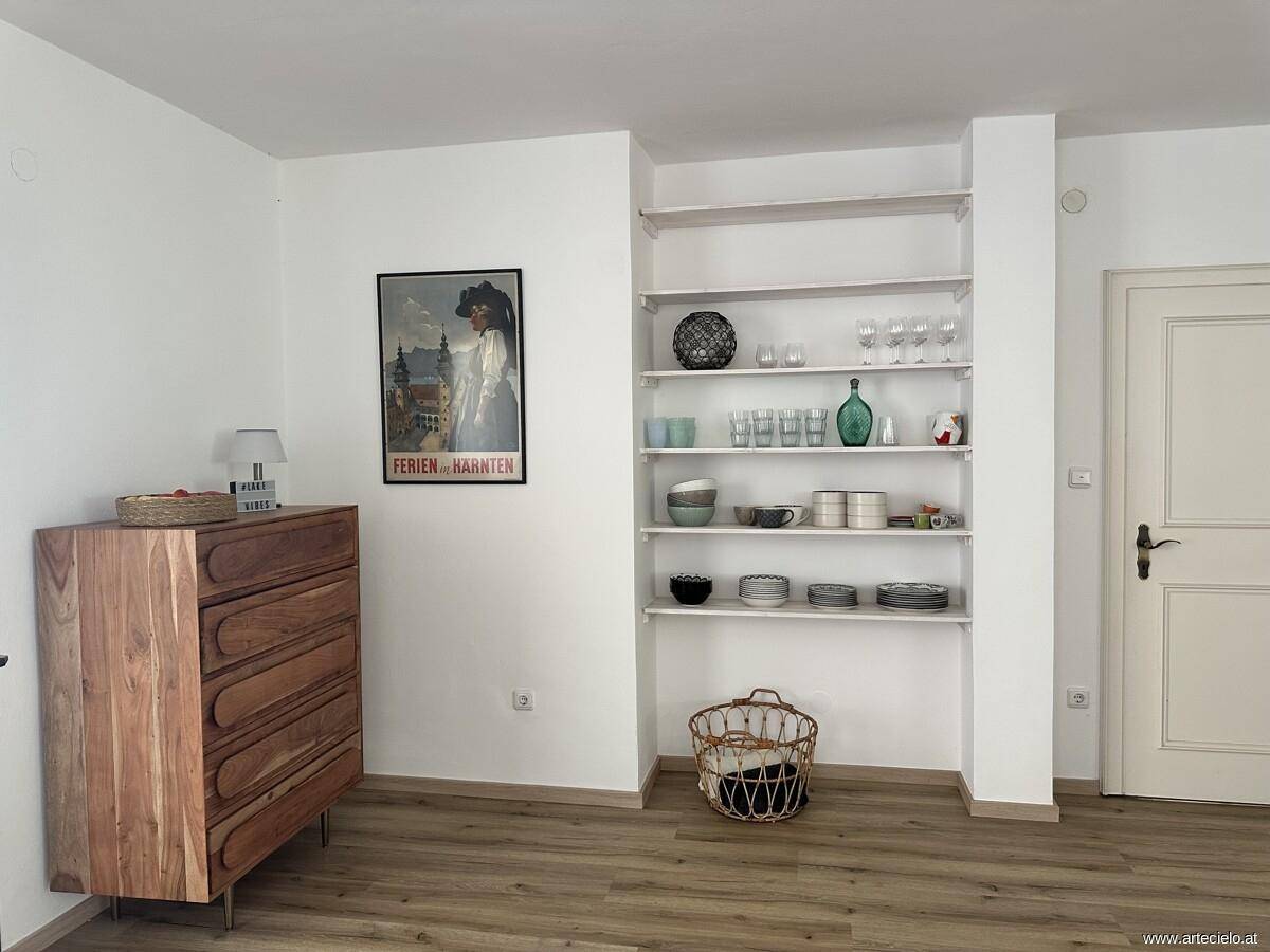 Flur mit Holzboden, Kommode und offenen Regalen für Geschirr und Dekoration.