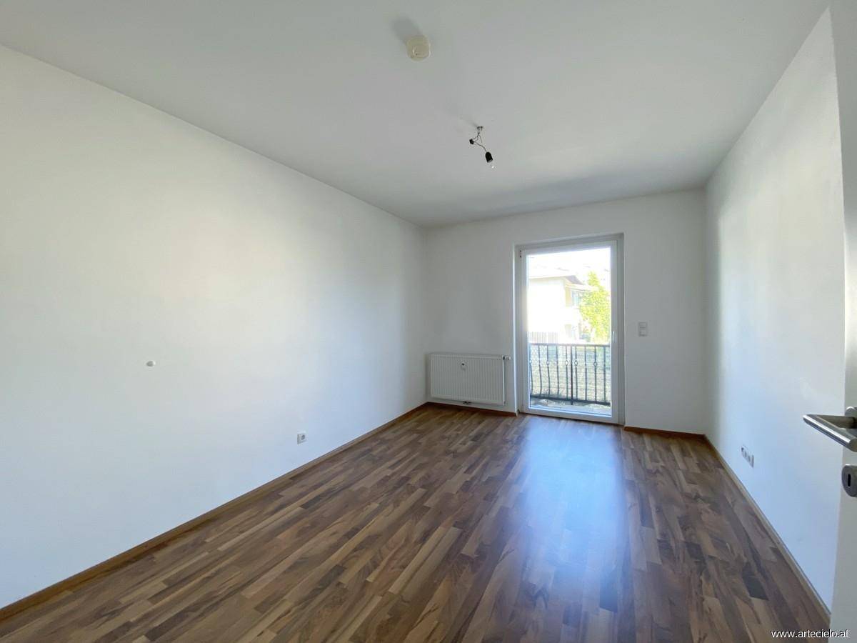 Helles Schlafzimmer mit neuem Laminatboden und Zugang zu einem kleinen französischen Balkon.