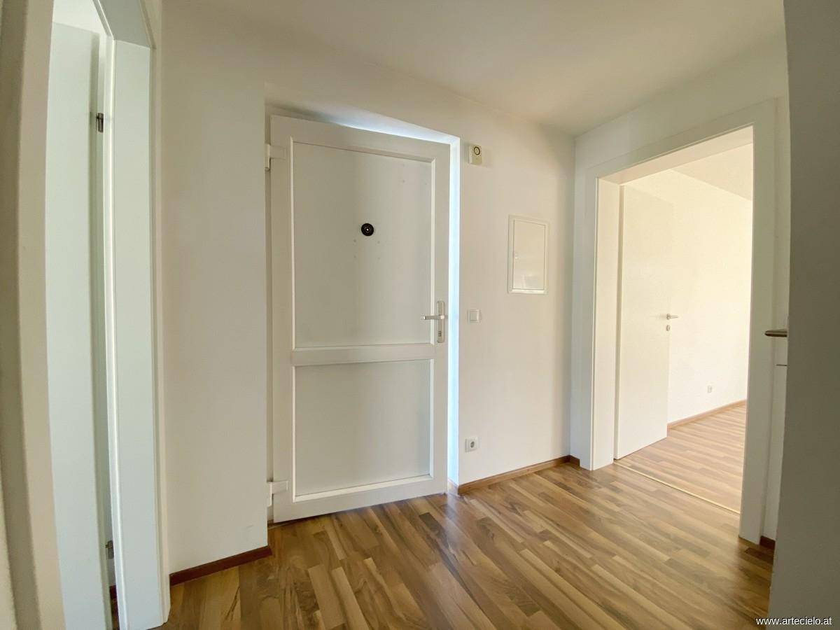Heller Flur mit Laminatboden und weißen Türen, der zu verschiedenen Räumen führt.