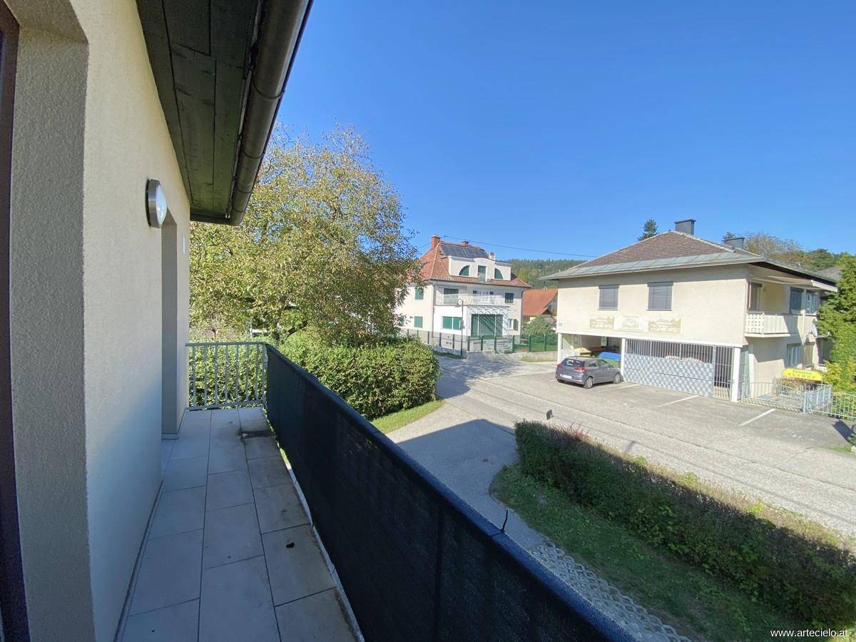 Sonniger Balkon mit Fliesen und Blick auf die Nachbarschaft und die umliegenden Gebäude.