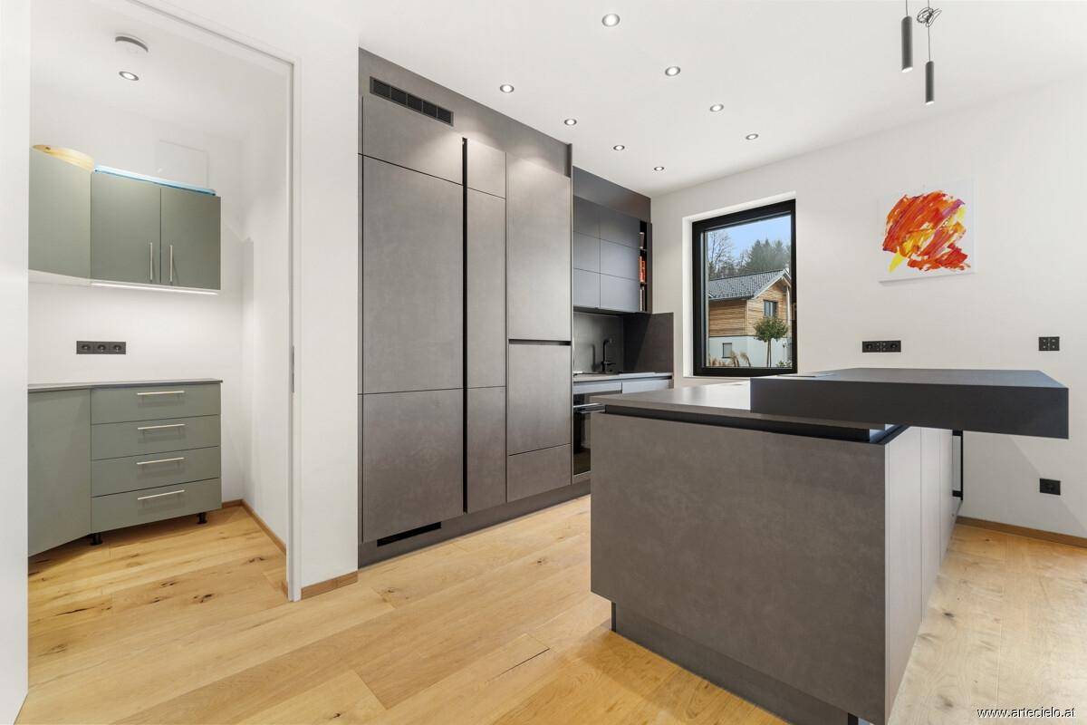 Moderne Küche mit grauen Fronten, integrierten Geräten und Holzboden.