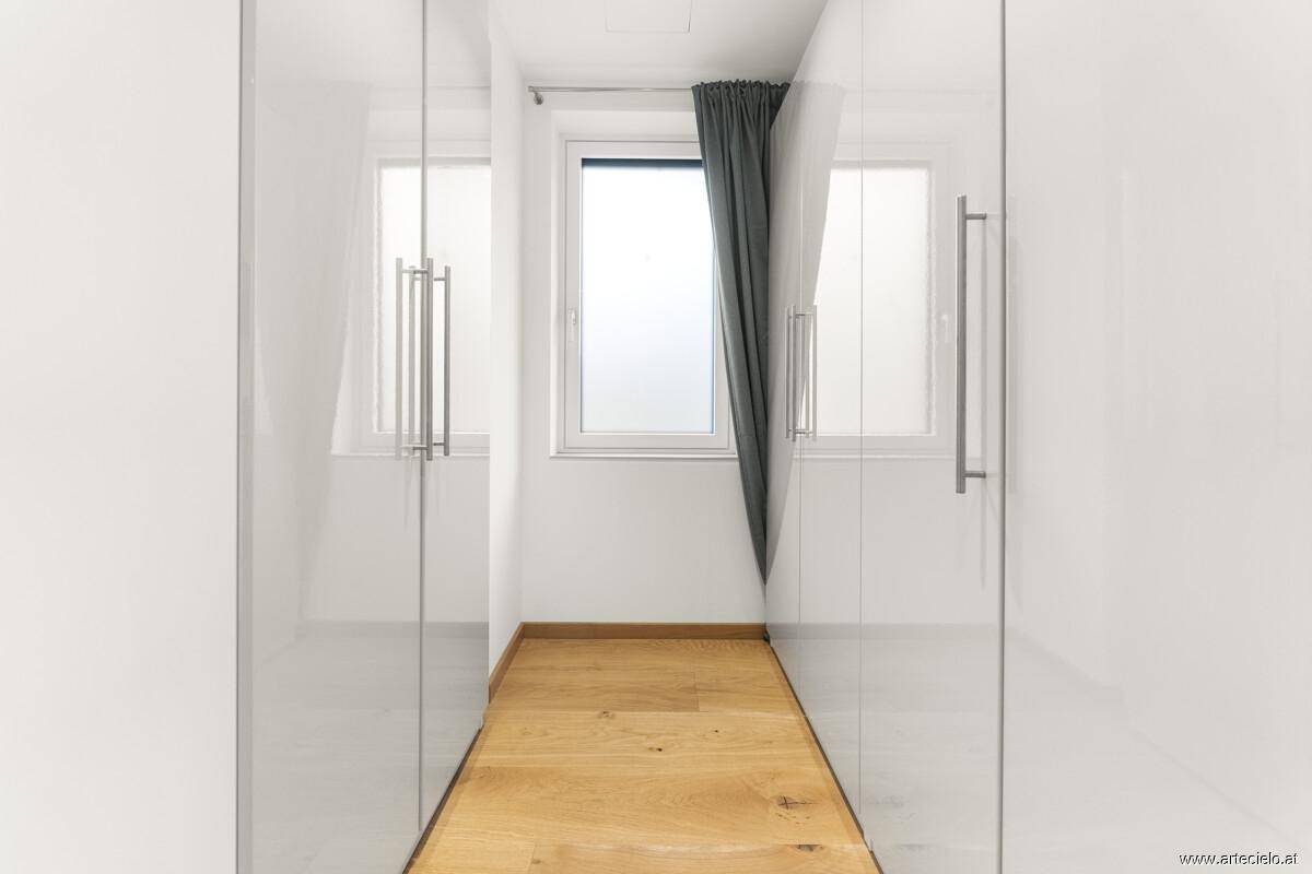 Heller Ankleidebereich mit Einbauschränken und Fenster.