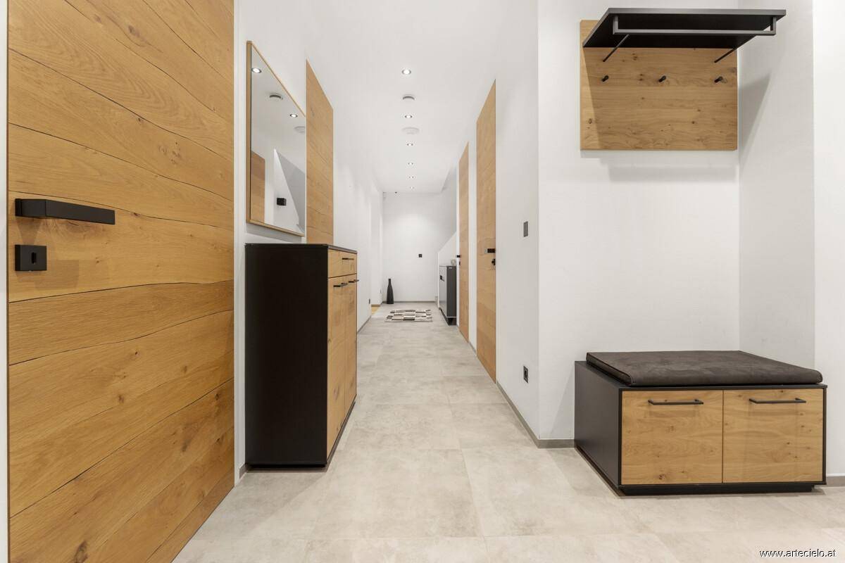 Heller Flur mit modernen Holzmöbeln, Spiegel und Fliesenboden.