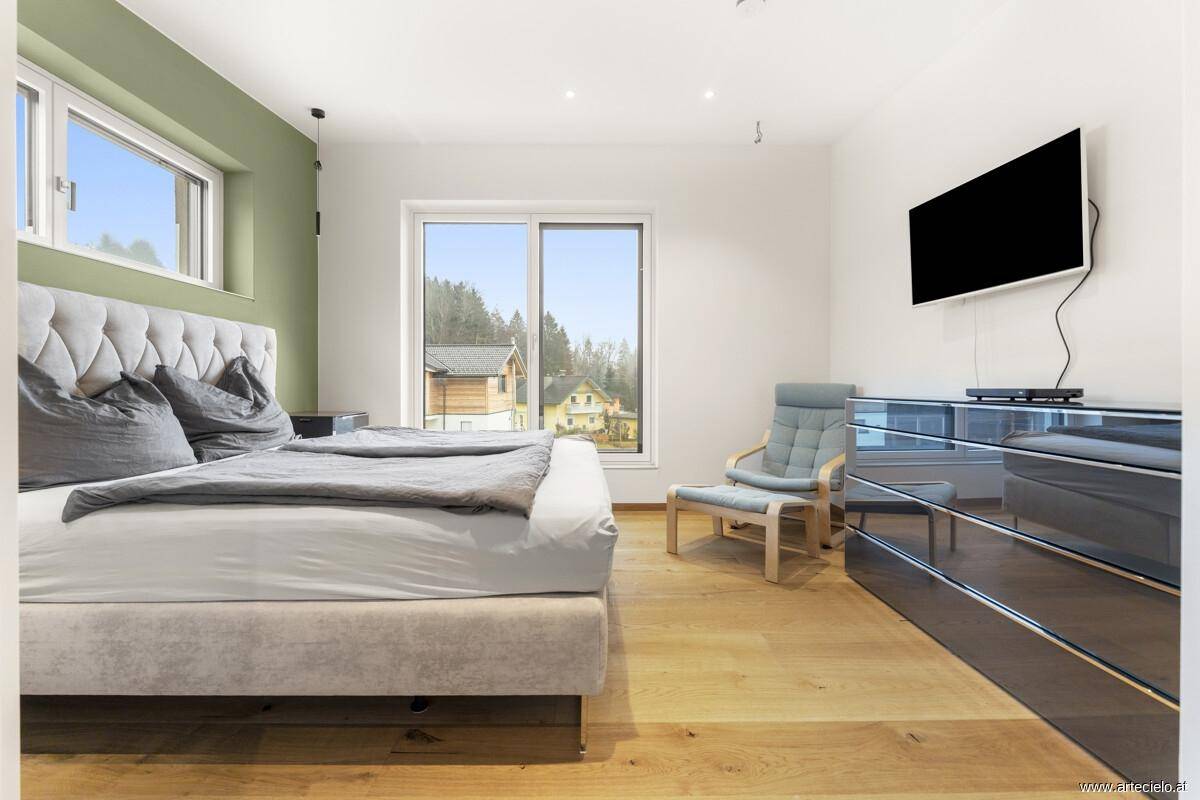 Helles Schlafzimmer mit großem Bett, Holzboden und Blick ins Grüne.