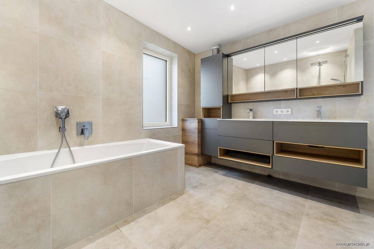 Modernes Badezimmer mit Badewanne, Doppelwaschbecken und großem Spiegelschrank.