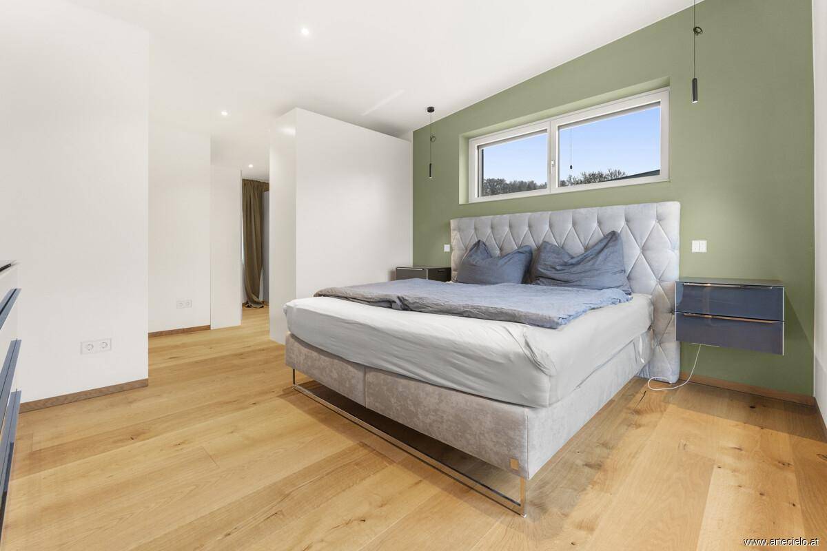 Geräumiges Schlafzimmer mit Doppelbett, Holzboden und grüner Akzentwand.