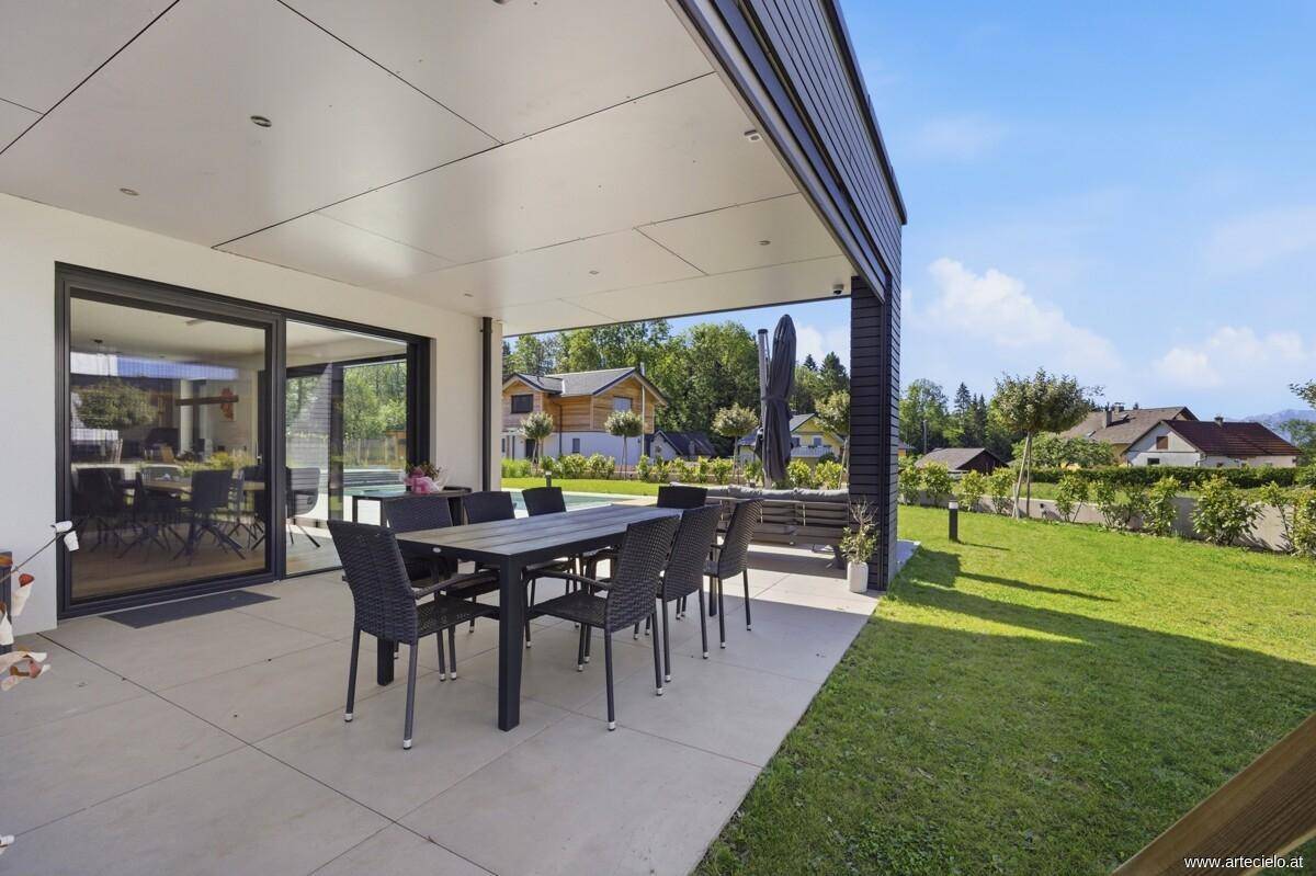 Überdachte Terrasse mit großem Esstisch und Blick in den Garten.