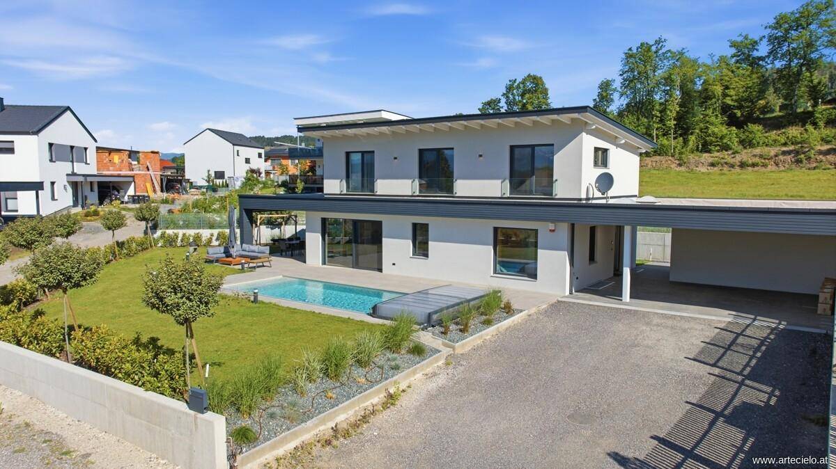 Modernes Einfamilienhaus mit Pool, Carport und gepflegtem Vorgarten.