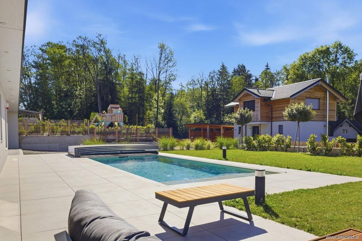 Großer Garten mit Pool, Liegefläche und Blick auf die umliegende Natur.
