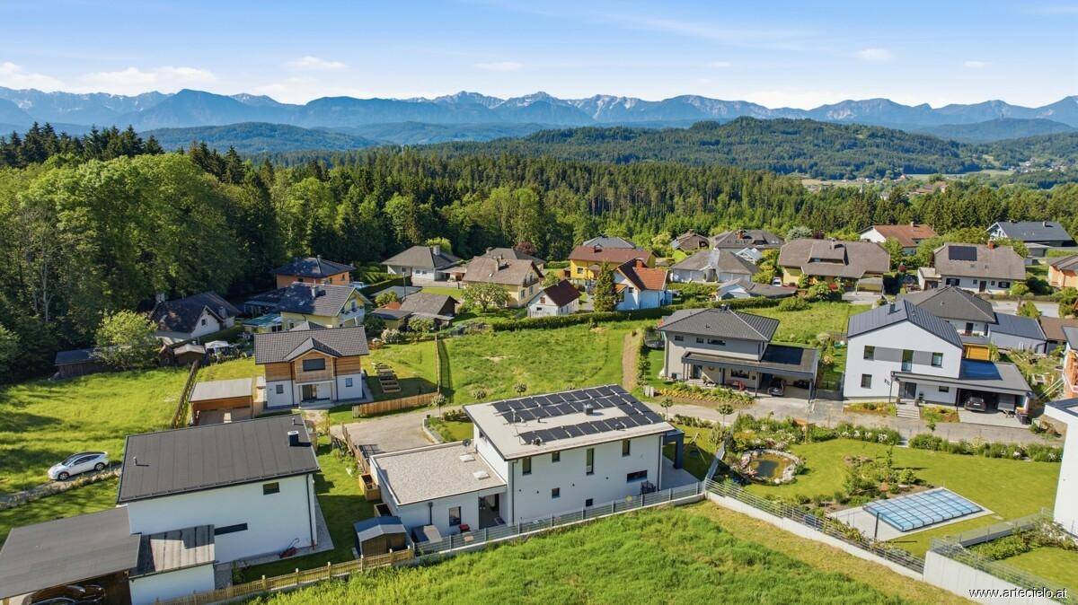 Luftaufnahme der Wohnsiedlung mit Bergen im Hintergrund und viel Grün.