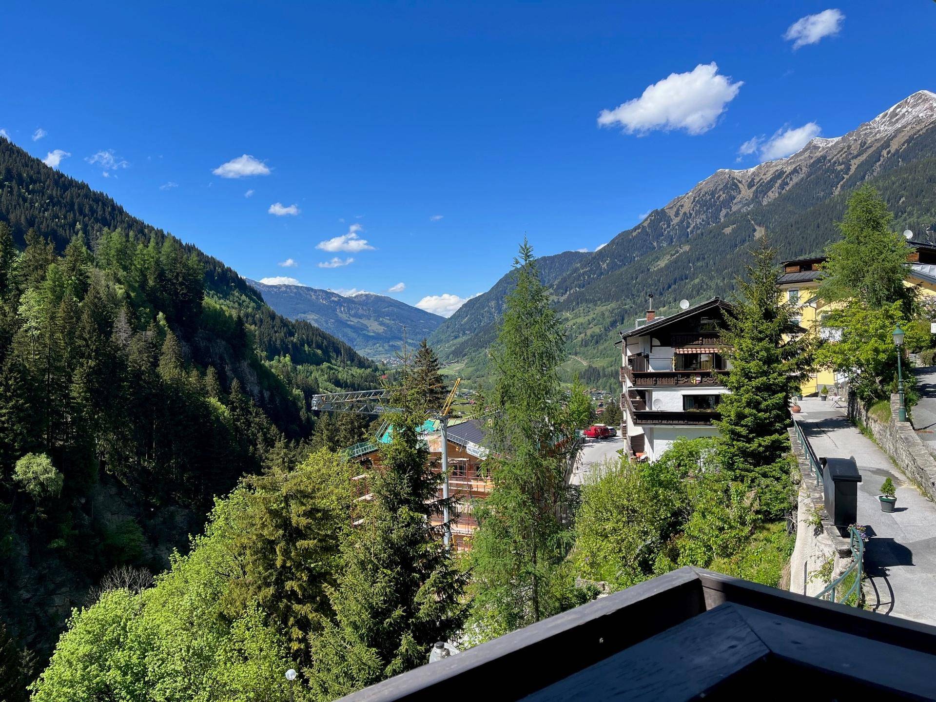 Panoramablick auf die majestätischen Alpen und das grüne Tal von einem Balkon aus.