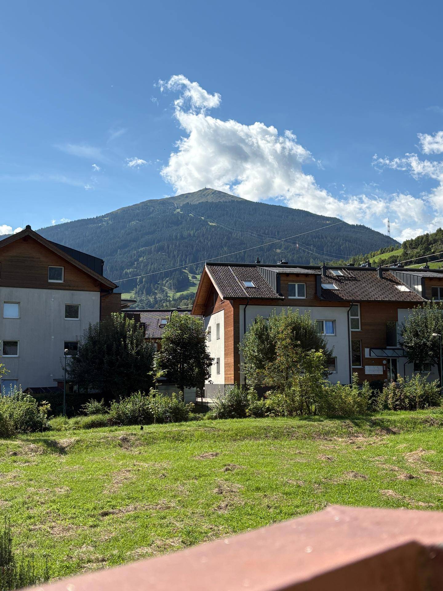 Panoramablick auf die umliegenden Berge und grüne Landschaft unter einem strahlend blauen Himmel.