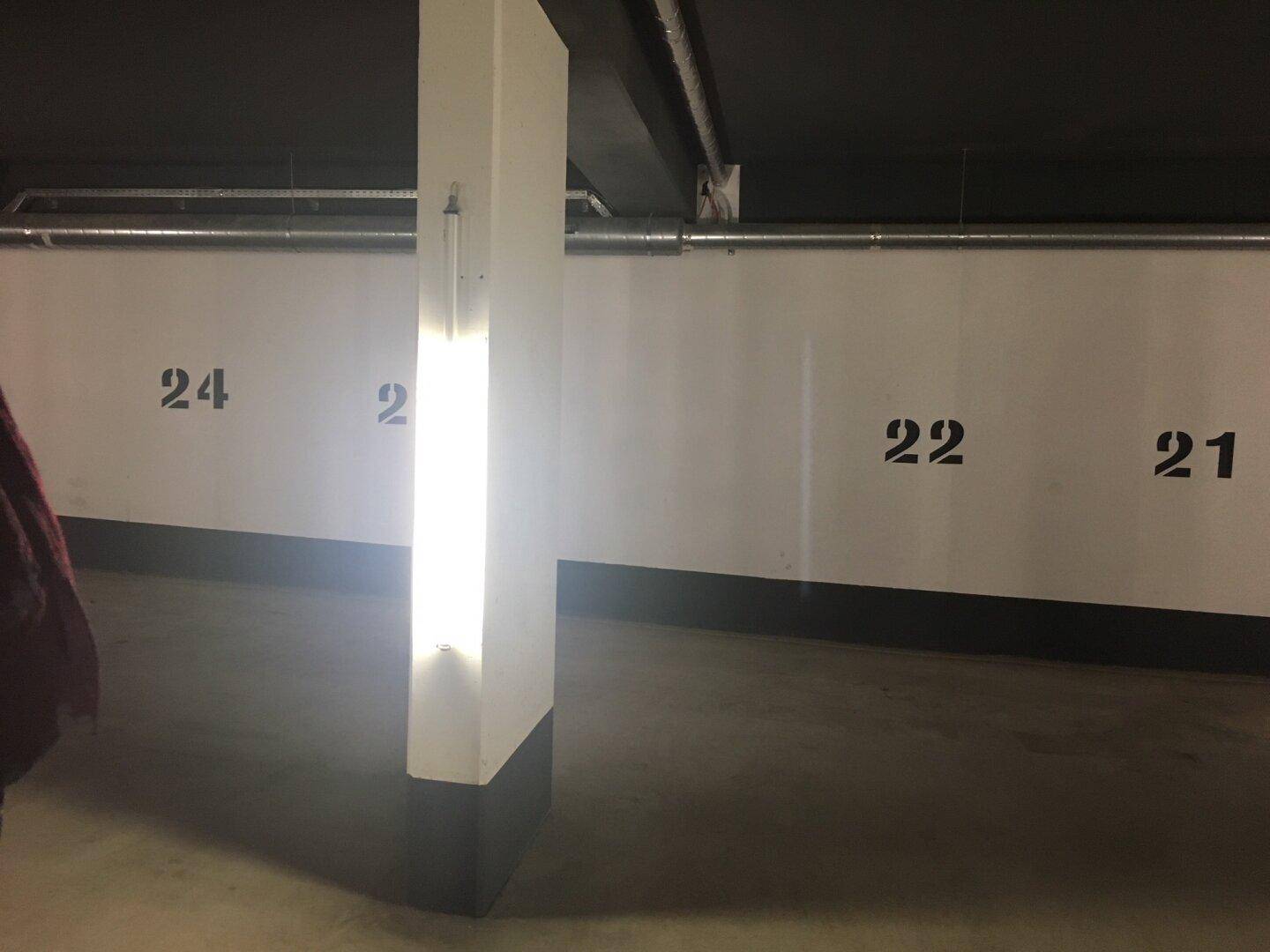 Tiefgarage mit nummerierten Stellplätzen und heller Beleuchtung.