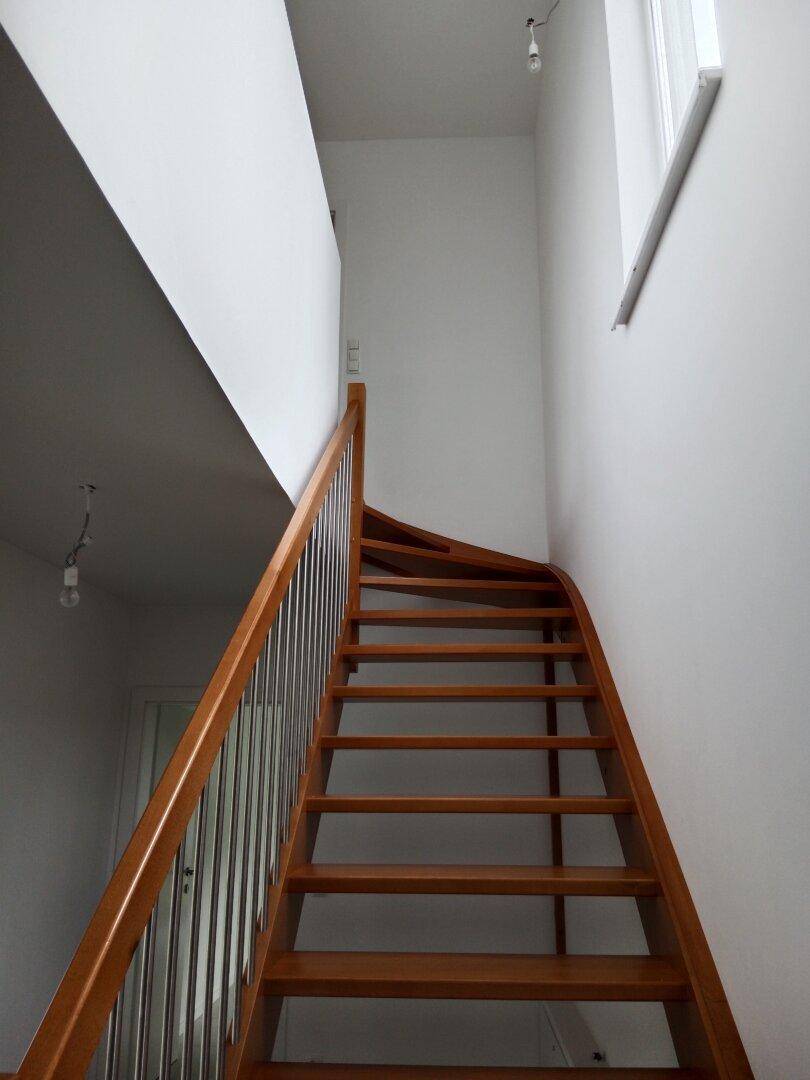 Elegante Holztreppe mit modernen Metallgeländern, die in die obere Etage führt.