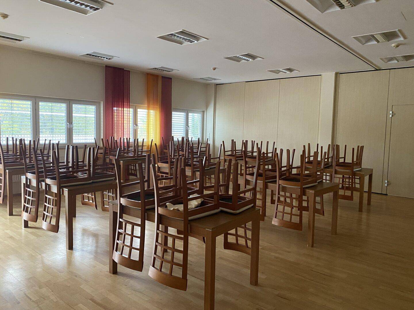 Großer Konferenzraum oder Speisesaal mit vielen Tischen und Stühlen, bereit für eine Veranstaltung oder Tagung.