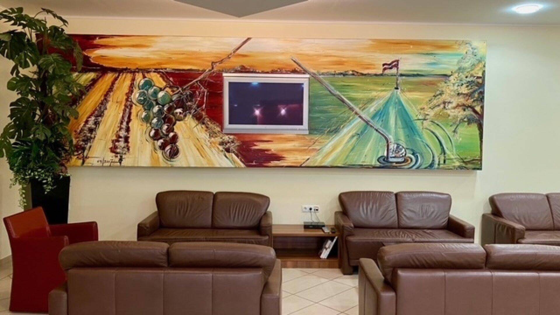 Geräumiger Gemeinschaftsbereich mit bequemen Ledersofas und einem großen, farbenfrohen Wandgemälde mit integriertem Fernseher.