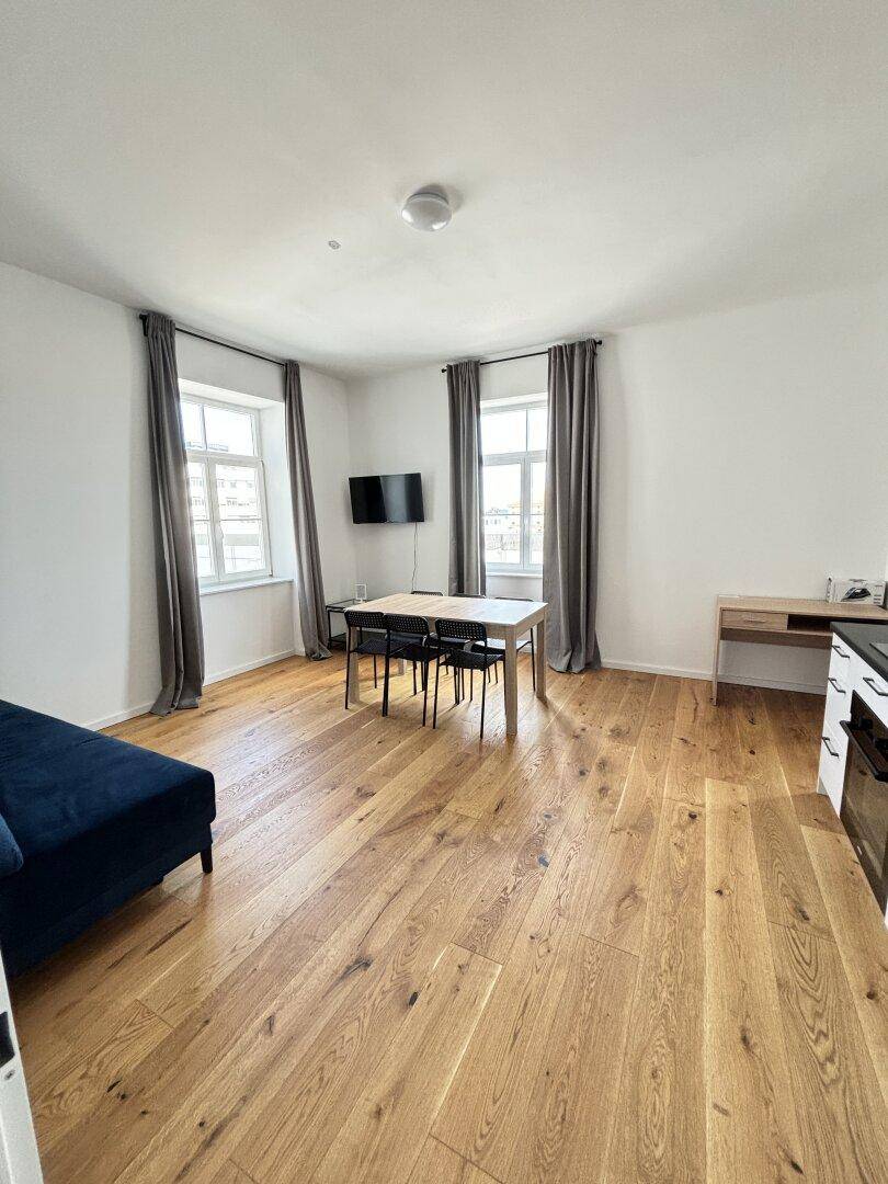Heller offener Wohn-Essbereich mit Holzboden, Esstisch und Sofa.