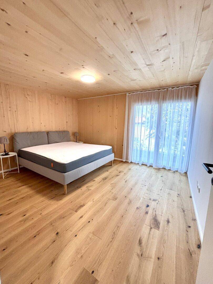 Helles Schlafzimmer mit Holzwänden, Holzdecke und Holzboden, ausgestattet mit einem modernen Bett.