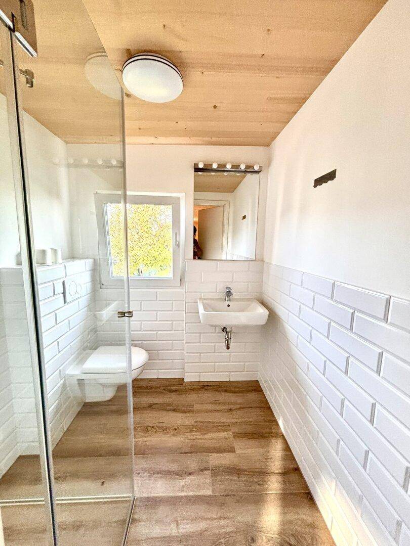 Modernes Badezimmer mit weißen Metrofliesen, begehbarer Dusche und Fenster für Tageslicht.