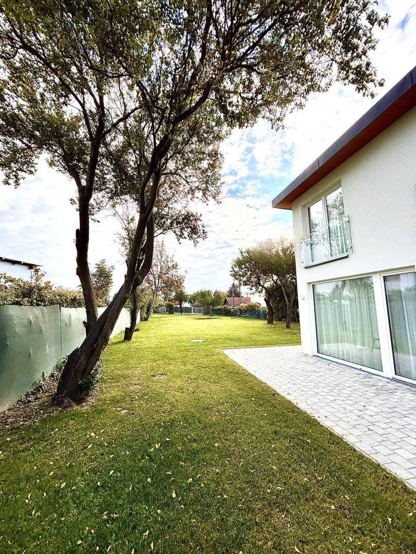 Weitläufiger grüner Gartenbereich neben dem Haus mit altem Baumbestand und viel Rasenfläche.