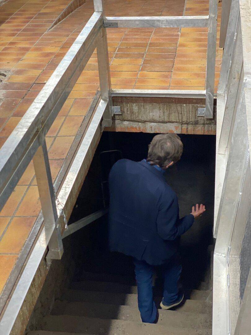 Person steigt eine Treppe hinunter in einen Kellerbereich mit gefliestem Boden oben.