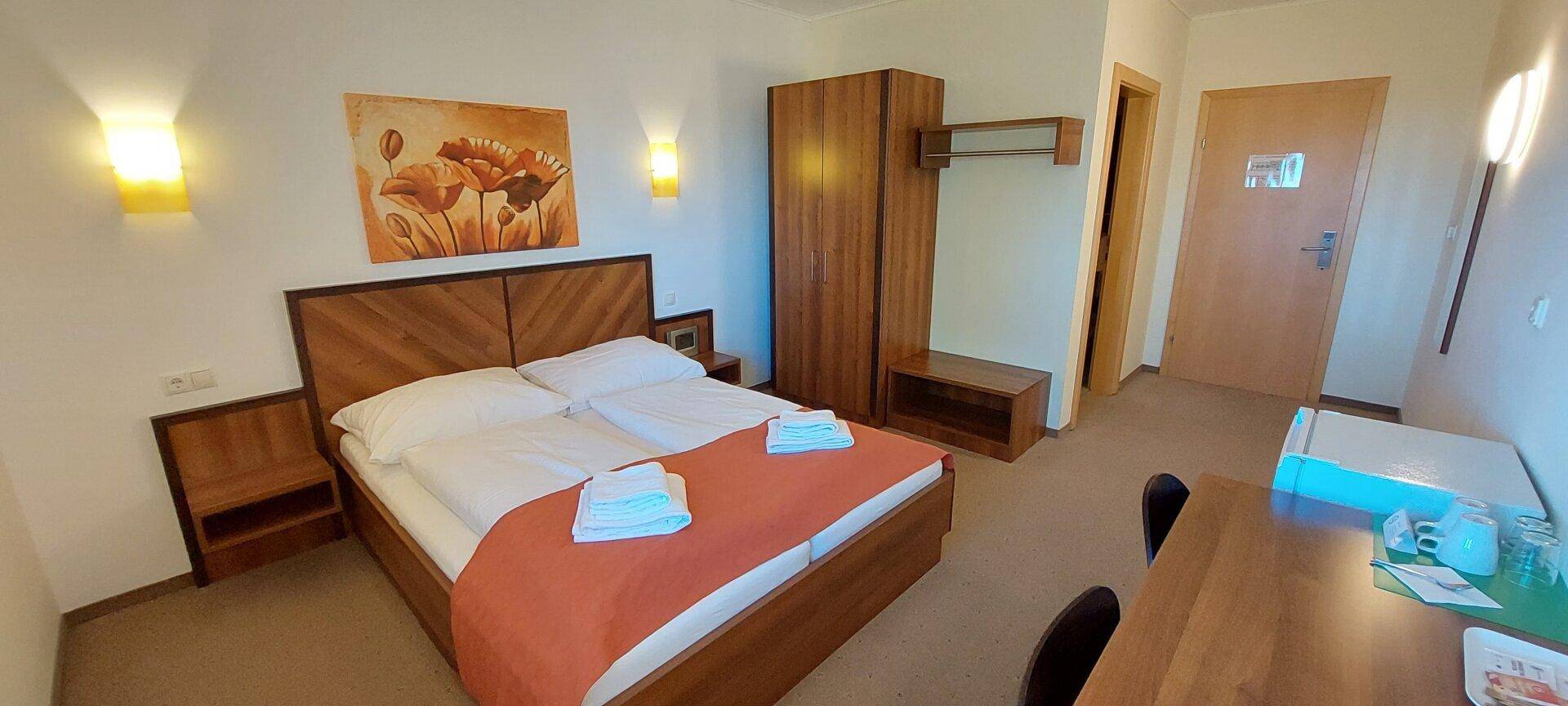 Gemütliches Schlafzimmer mit Doppelbett, Holzmöbeln und einem kleinen Essbereich.