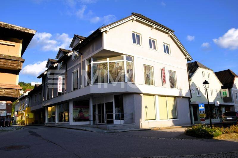 Eckgebäude mit großen Schaufenstern und traditioneller Architektur in einer städtischen Umgebung.