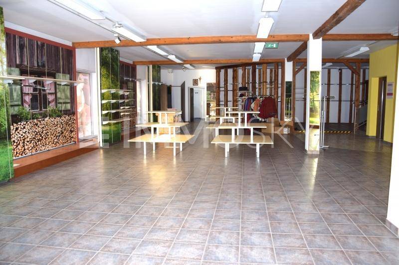 Großer, leerer Raum mit Fliesenboden, Holzbalken und Wanddekorationen.