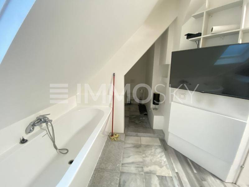 Modernes Badezimmer mit Badewanne, Dachschräge und großformatigen Fliesen.