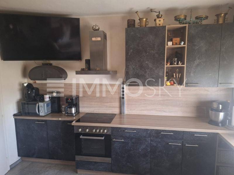 Moderne Küche mit dunklen Schränken, Holzarbeitsplatte und integrierten Geräten.