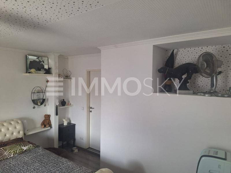 Schlafzimmer mit weiß gestrichenen Wänden, integrierten Regalen und modernem Dekor.