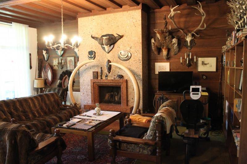 Gemütliches Wohnzimmer mit Kamin, rustikalen Holzvertäfelungen und bequemen Möbeln mit Fellbezug.