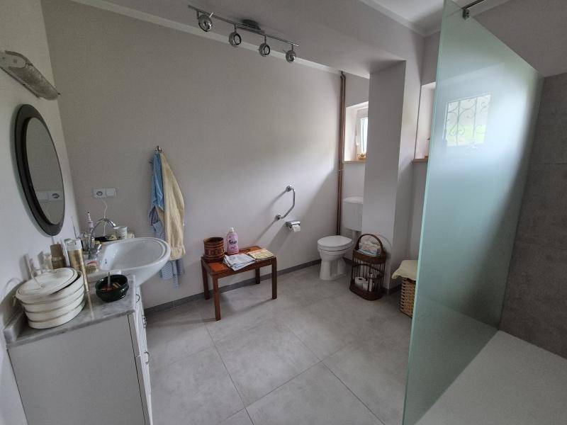 Modernes Badezimmer mit ebenerdiger Dusche, Haltegriffen und einem Fenster für natürliches Licht.