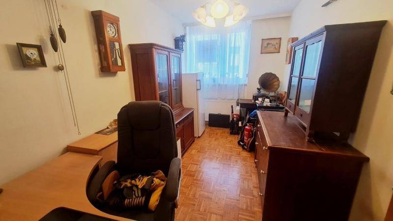 Helles Arbeitszimmer mit Parkettboden, Holzmöbeln und einem Fenster mit Blick ins Grüne.