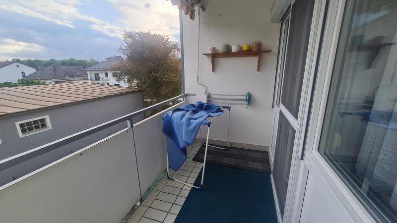 Kleiner Balkon mit Fliesenboden, Wäscheständer und Blick auf die umliegenden Dächer.