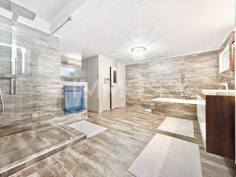 Modernes Badezimmer mit großer Dusche, Badewanne, Sauna und eleganten Fliesen.