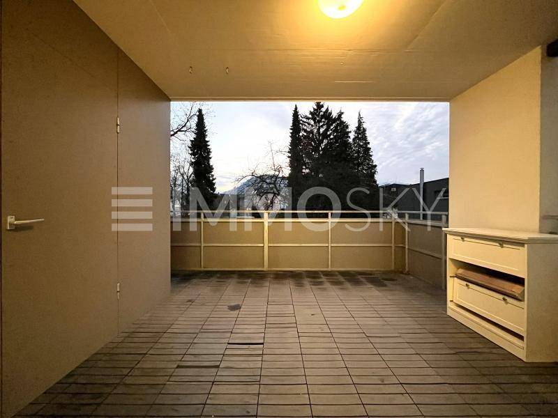 Überdachter Balkon mit Fliesenboden und Blick auf Bäume und die umliegende Landschaft.