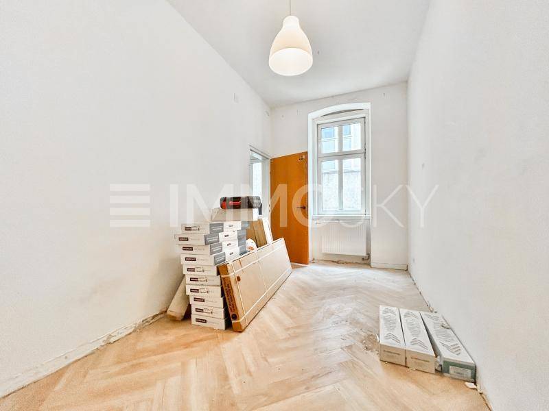 Heller Raum in Renovierung mit Fischgrätparkettboden und einem großen Fenster.