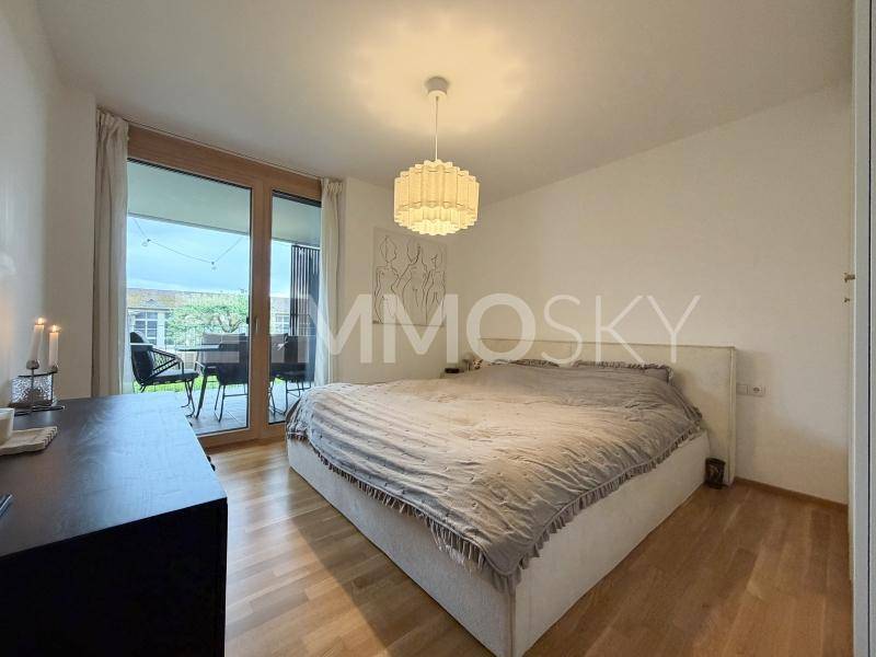 Gemütliches Schlafzimmer mit großem Bett, Holzboden und direktem Zugang zum Balkon.