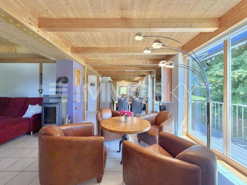 Heller Wohn- und Essbereich mit Holzbalkendecke, Kaminofen und Zugang zum Balkon.