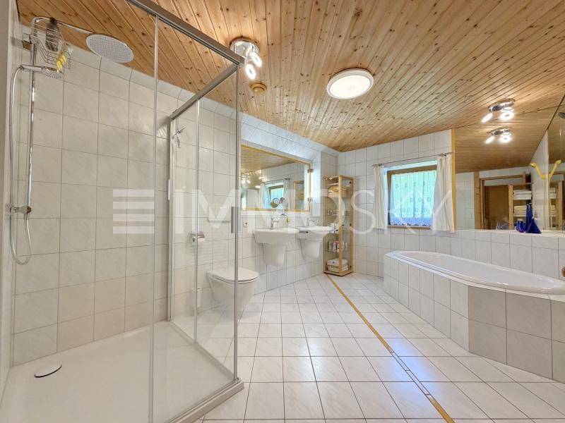 Geräumiges Badezimmer mit Dusche, Badewanne, Doppelwaschbecken und Holzdecke.