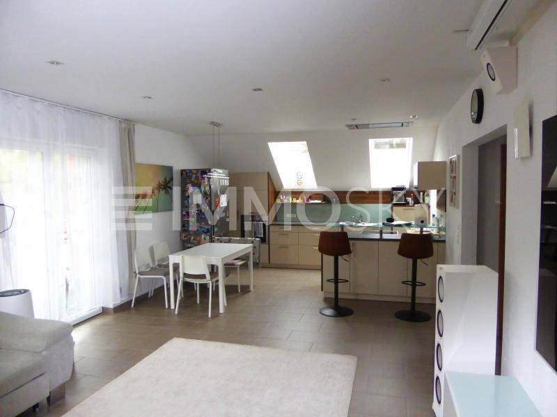 Heller offener Wohn-Essbereich mit integrierter Küche, Dachfenstern und Zugang zur Terrasse.