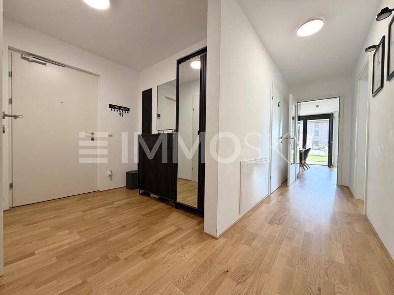Geräumiger Flur mit Holzboden, großem Spiegel und Garderobe, der zu weiteren Räumen führt.