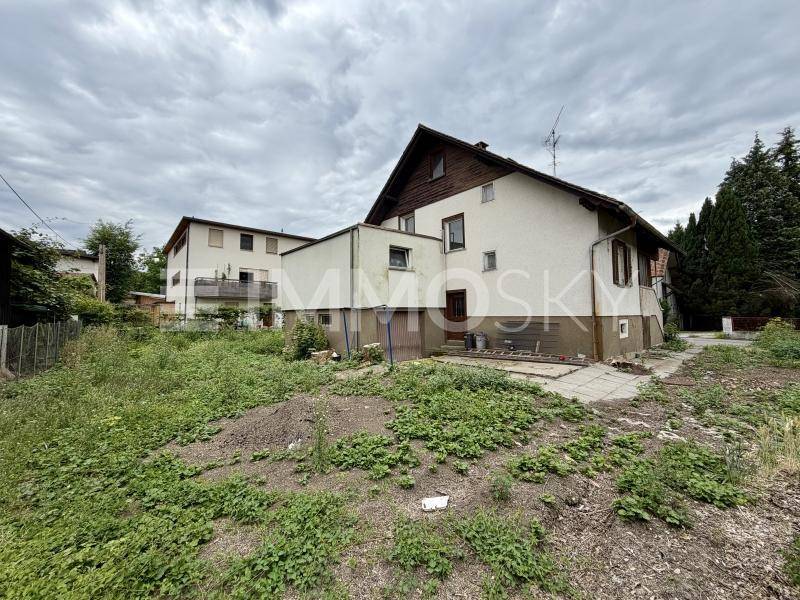 Rückansicht des Hauses mit Anbau und ungenutztem Grundstücksbereich.