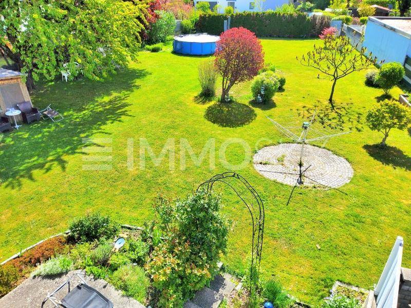 Überblick über den weitläufigen Garten mit Rasen, Bäumen, einem Aufstellpool und Wäschespinne.