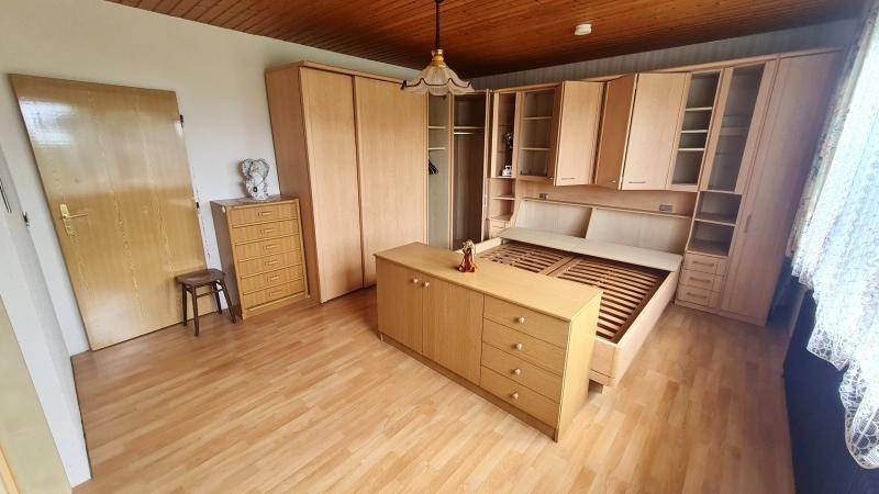 Schlafzimmer mit Einbauschränken, Holzmöbeln und Parkettboden in hellem Holzton.