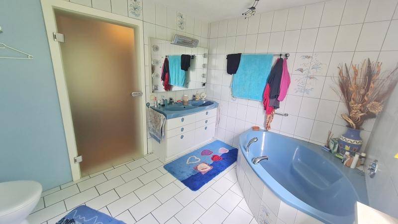 Badezimmer mit blauer Eckbadewanne, Einzelwaschbecken und weißen Fliesen.